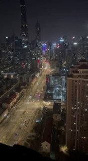 Вертикальное ночное фото вида на улицу и освещённые высотки Шанхая из окна или с высоты, движение машин и неоновая подсветка городской магистрали.