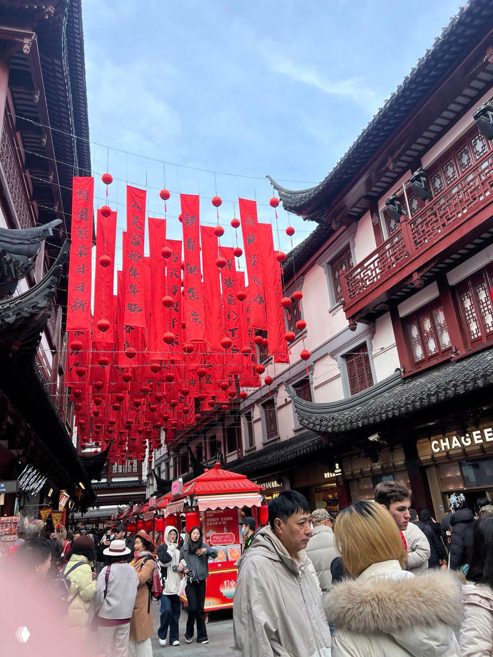 Узкая туристическая улица, украшенная десятками красных фонарей и полотнищ, много людей, старинная архитектура и сувенирные лавки — атмосферный традиционный рынок.