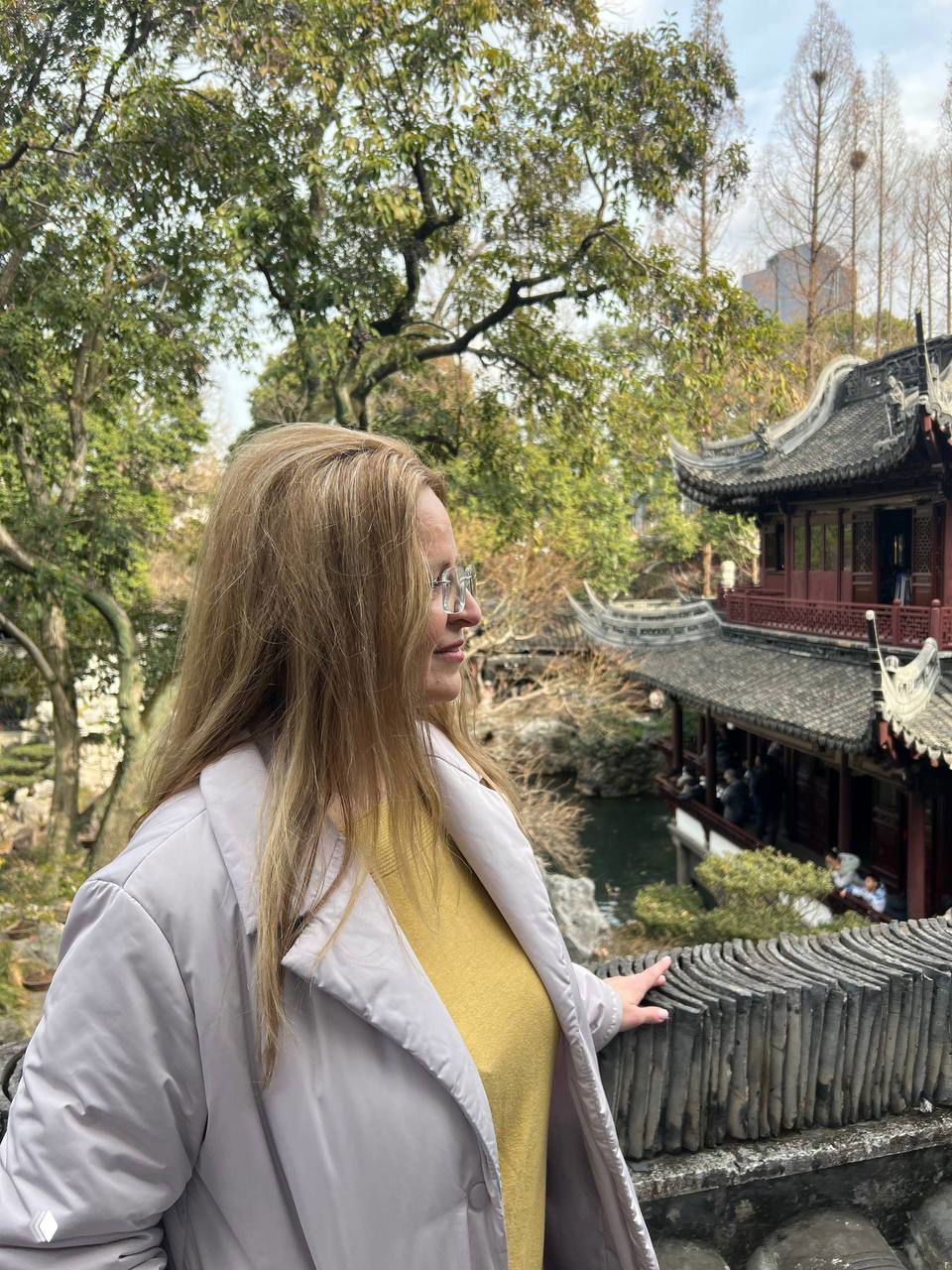 Профиль женщины на фоне традиционного китайского сада и деревянной архитектуры: мосты, вода и растительность создают спокойный культурный контекст.