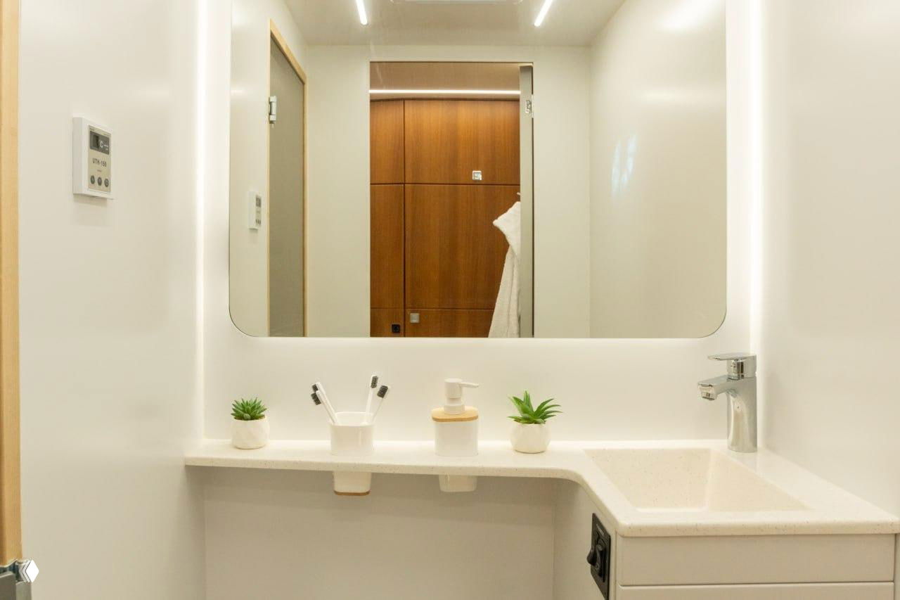 Современная компактная ванная комната автодома: раковина, зеркало и минималистичный белый интерьер для удобства в путешествиях.