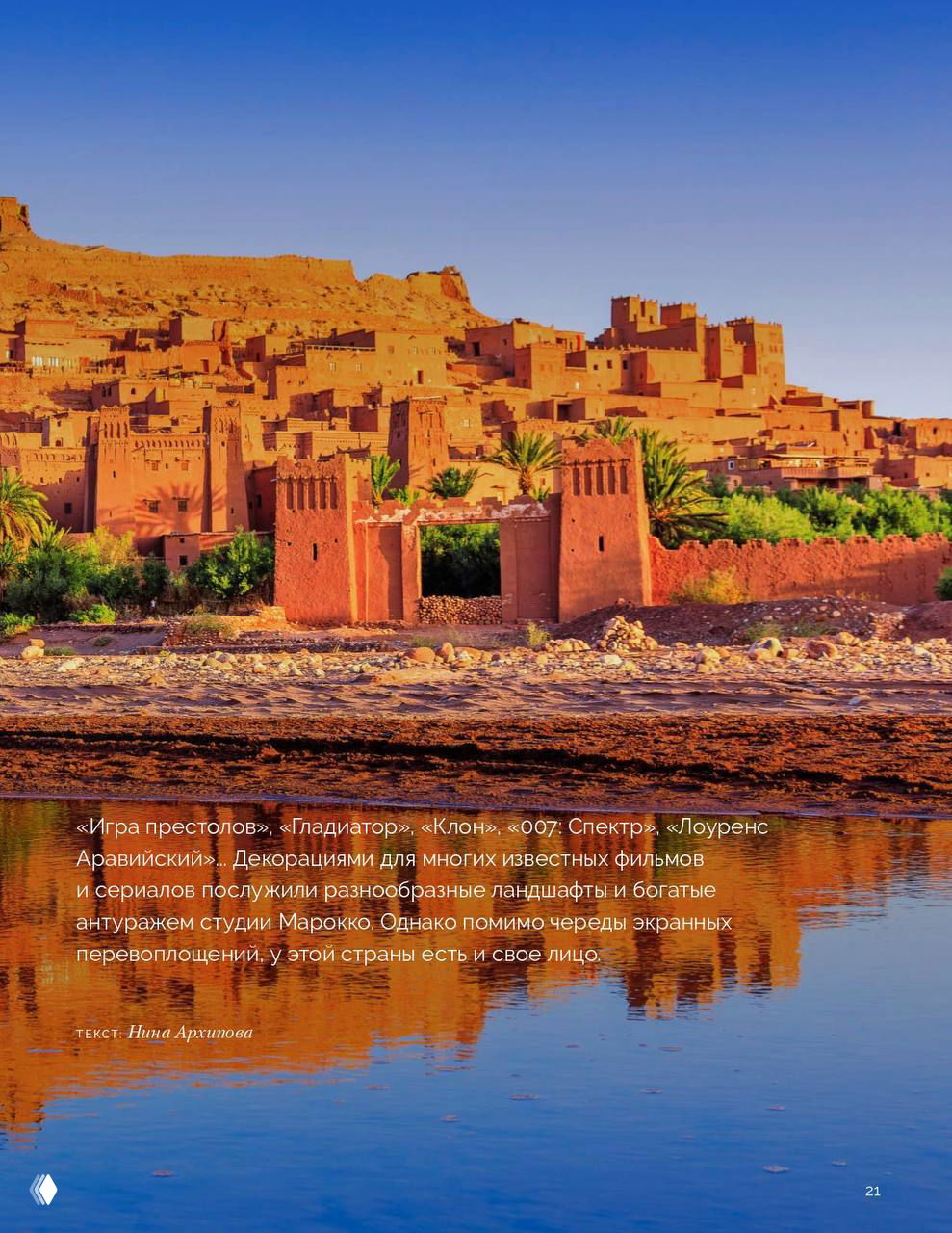 Панорамный вид на Уарзазат: красные глинобитные постройки на фоне голубого неба и зеркального отражения в воде у береговой линии