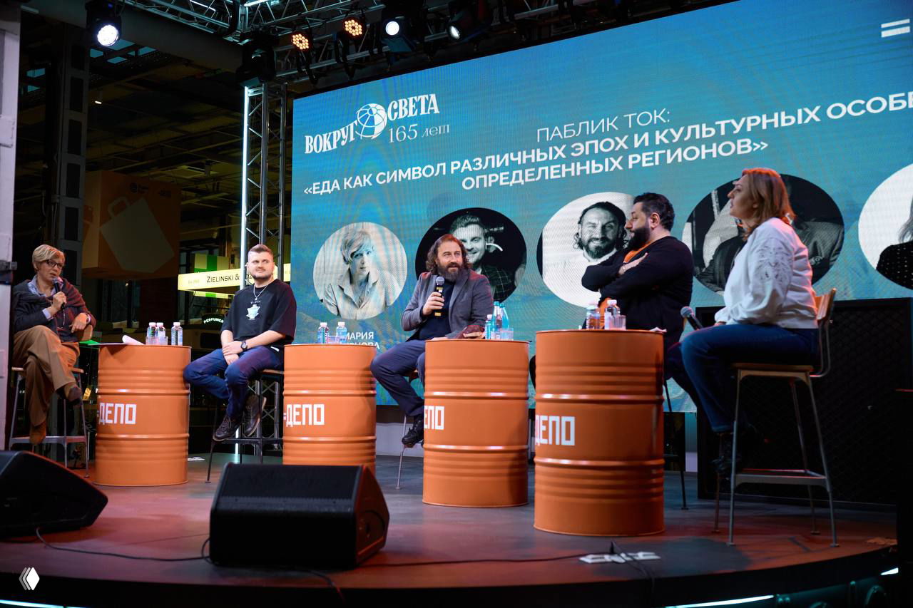 Паблик-ток на сцене: четыре спикера и ведущая сидят за бочками-столиками на фоне экрана с названием сессии про еду и культурные особенности регионов.