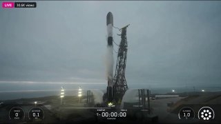 Ракета-носитель Falcon 9 на стартовой площадке в пасмурную погоду; кадр трансляции запуска при миссии Starlink, видна пусковая конструкция и дымовые следы.