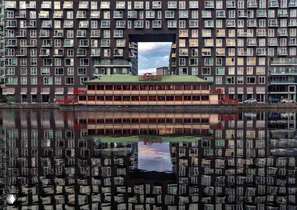 Городской пейзаж с фасадами домов и зеркальным отражением в канале; симметрия и архитектурные детали создают сильную композицию — финалист LCE 2026.