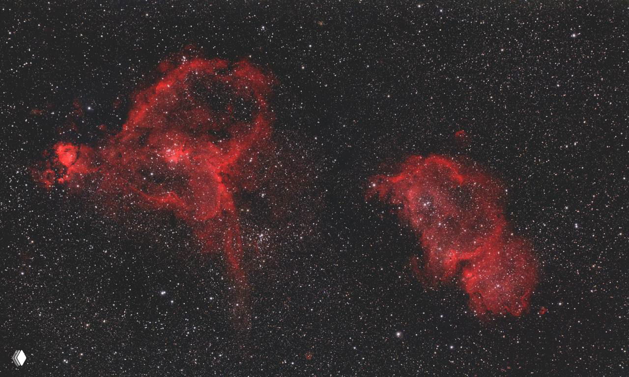 Широкое поле с двумя крупными красными эмиссионными туманностями рядом друг с другом — вероятно пара «Сердце» и «Душа» на фоне множества звёзд.