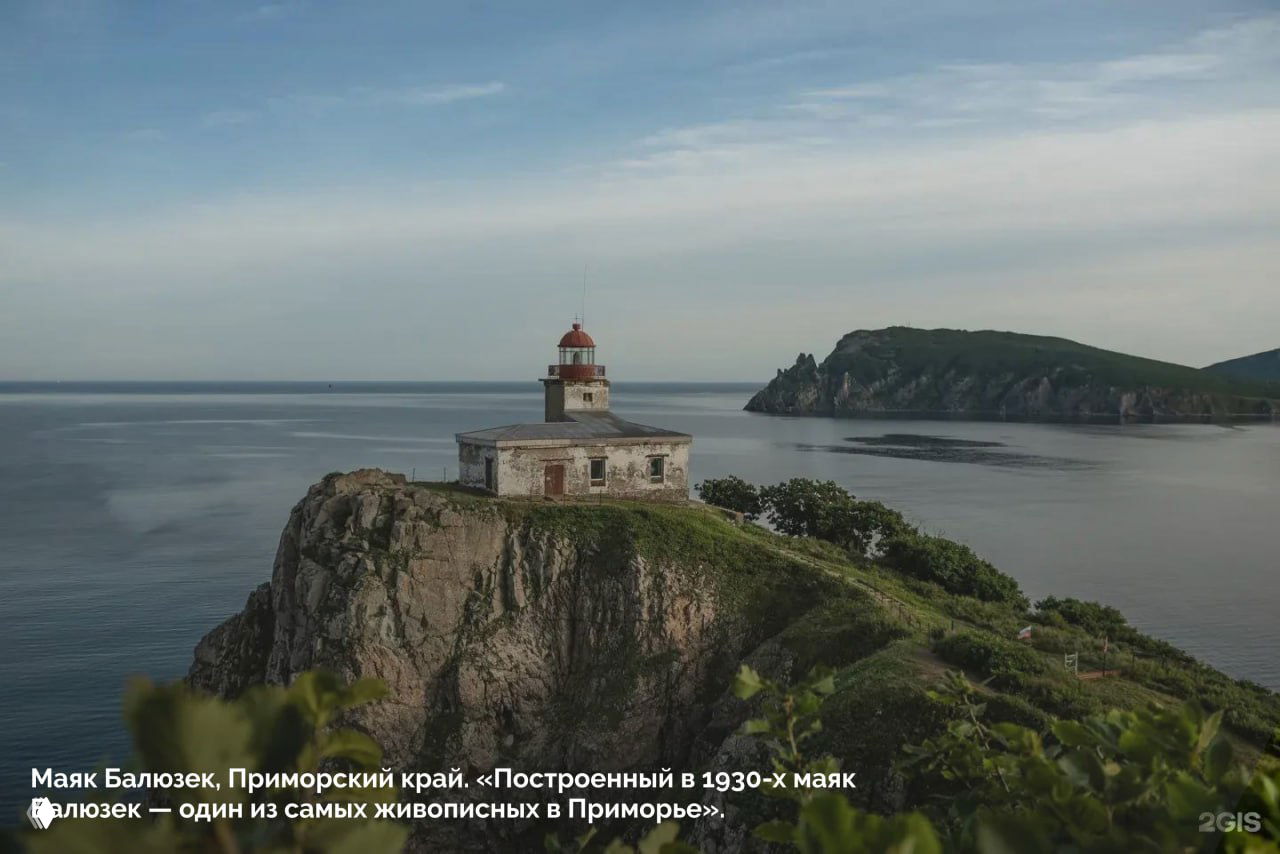 Маяк Баюзек в Приморском крае на скалистом утёсе у моря: старинное здание на фоне тихой бухты, снимок из подборки 2ГИС «100 кадров года».