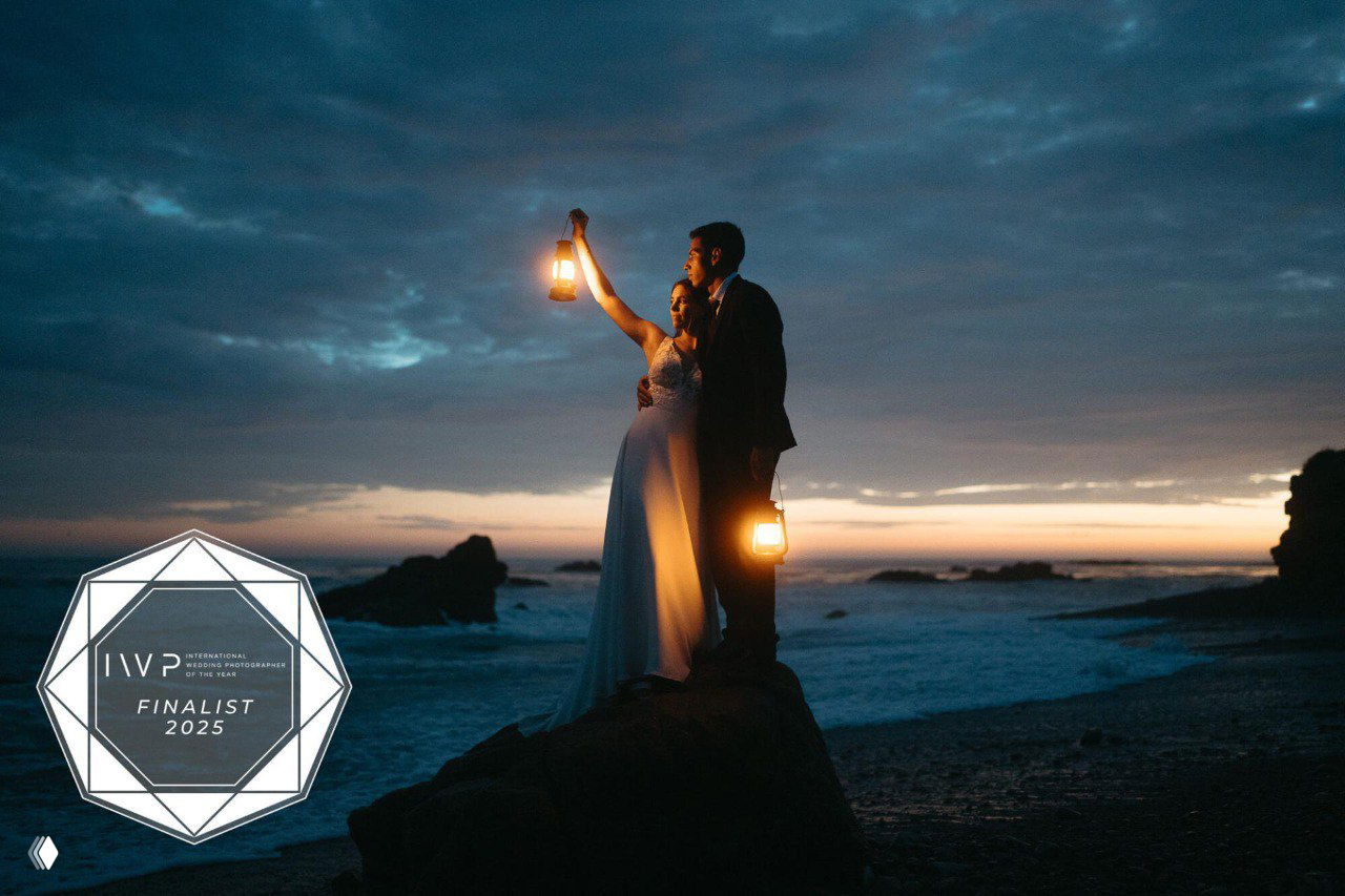 Пара на берегу океана на закате держит фонари: атмосферный свадебный кадр, темный небосвод и теплое освещение, отмечен как финалист.
