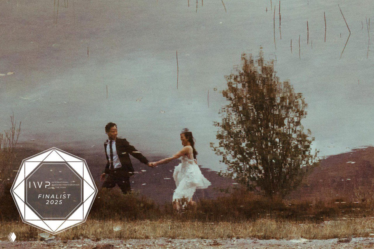 Молодая пара бежит по полю в свадебных нарядах — зернистая текстура и пейзаж в тёплых тонах, отмеченный знаком финалиста IWPOTY.