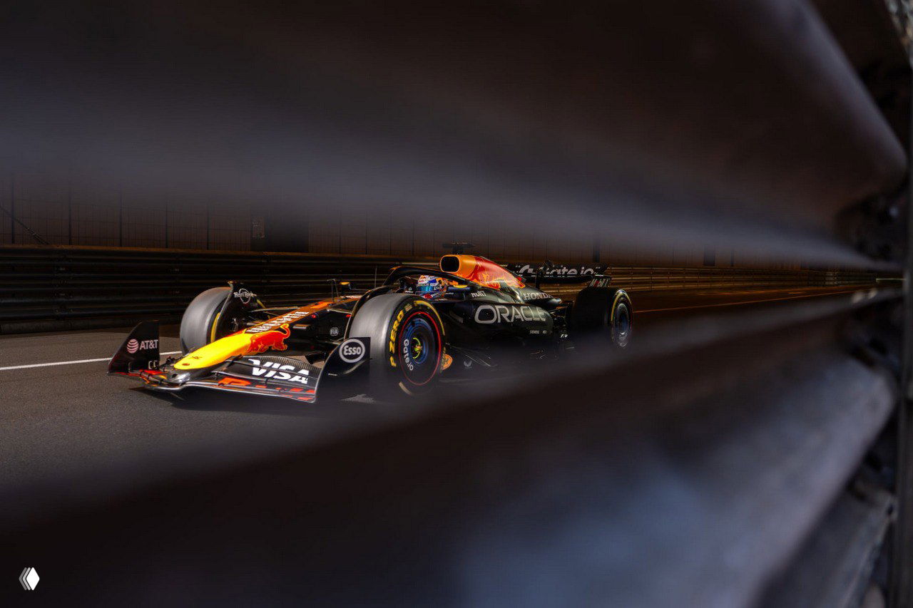 Гоночный болид Формулы 1 на трассе ночью, снятый через ограждение: художественный кадр с выделением скорости и фирменного дизайна команды, один из победных снимков.