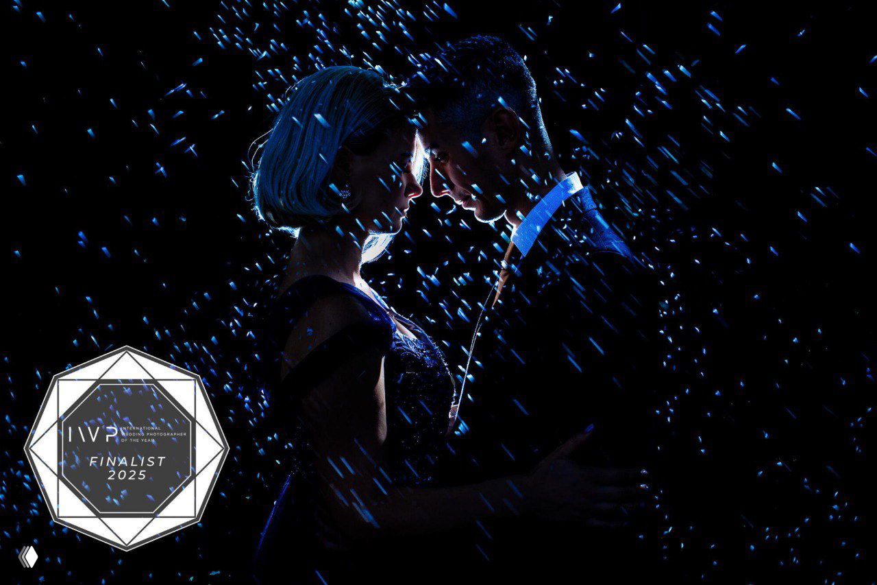 Контровой силуэт пары в дождевых или водяных брызгах на тёмном фоне — драматичный финалист конкурса свадебной фотографии 2025.