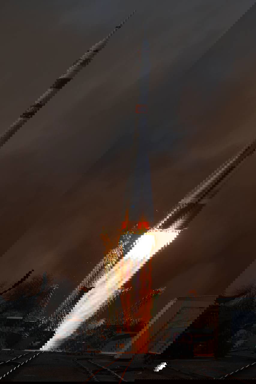 Ракета «Союз» в момент отрыва от стартовой площадки: мощный огненный шлейф, поднимающаяся колонна дыма и конструкции опорного механизма.