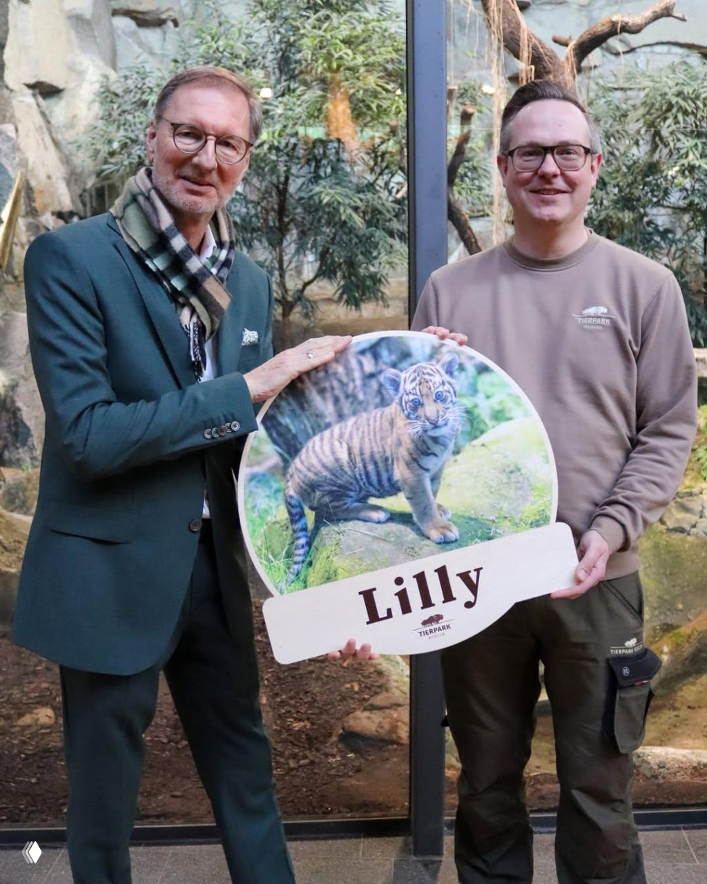 Двое сотрудников зоопарка держат табличку с фотографией тигрёнка и надписью «Lilly» на церемонии наречения имени, прошедшей 17 марта в Берлине.
