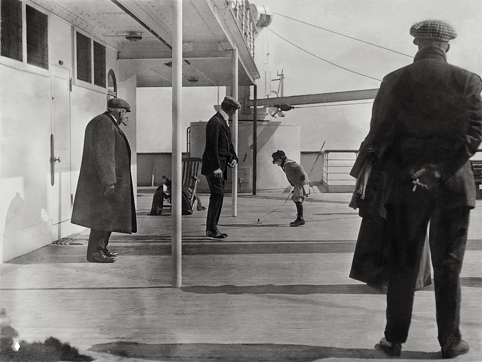 Черно-белая фотография палубы «Титаника»: пассажиры и мальчик, играющий на палубе; одежда и детали быта начала XX века.