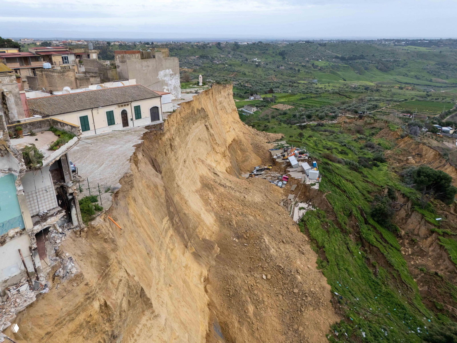 Аэрофотоснимок длинной кромки оползня в сельской зоне Сицилии с обрушившимися слоями грунта и завалами внизу.