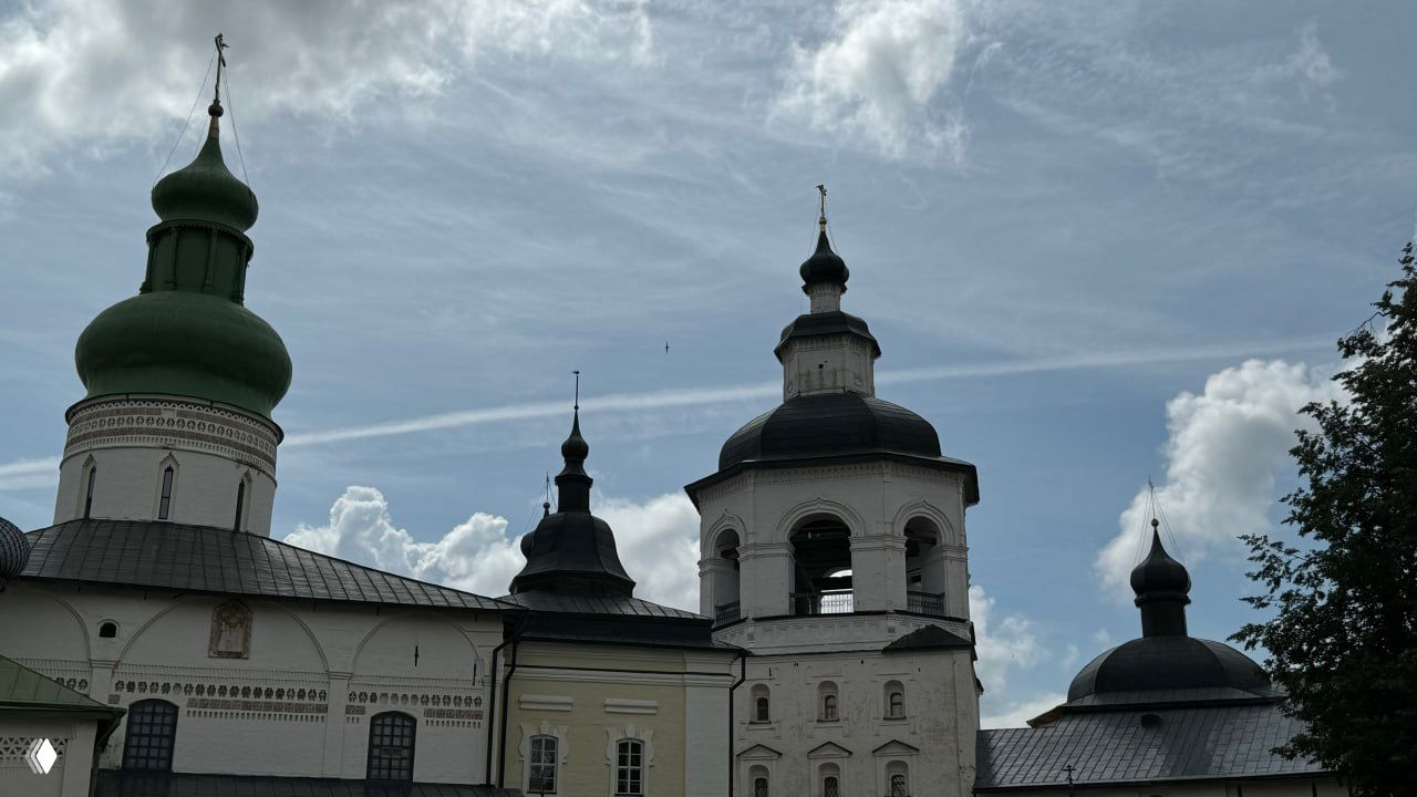 Набор куполов и звонница на фоне неба: декоративные детали фасадов, колокольня и окружающие постройки на территории Кирилло‑Белозерского монастыря.