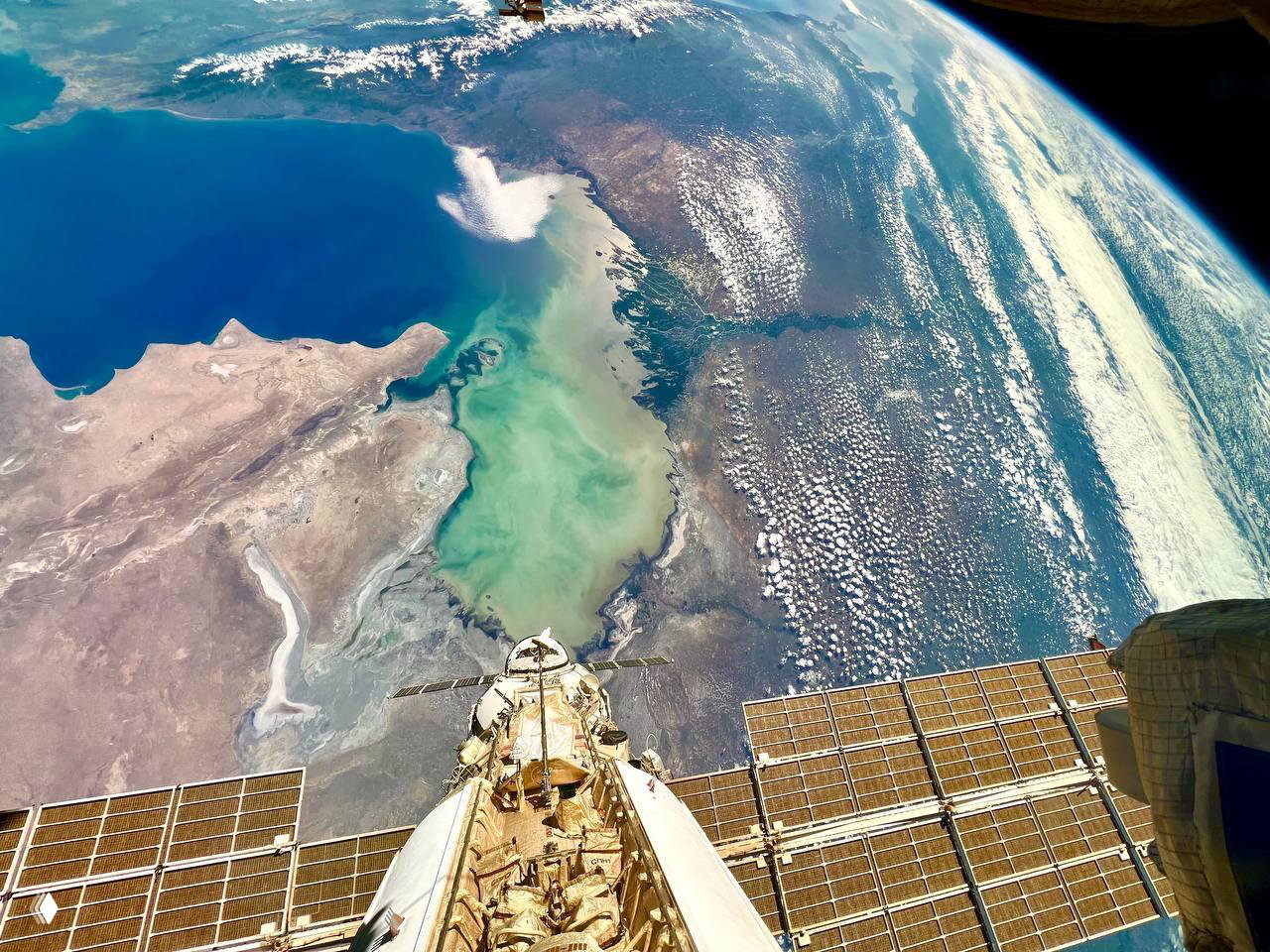 Вид Каспийского моря из космоса с сегментом солнечных панелей МКС на переднем плане; видны обмелевшие побережья и мелководья