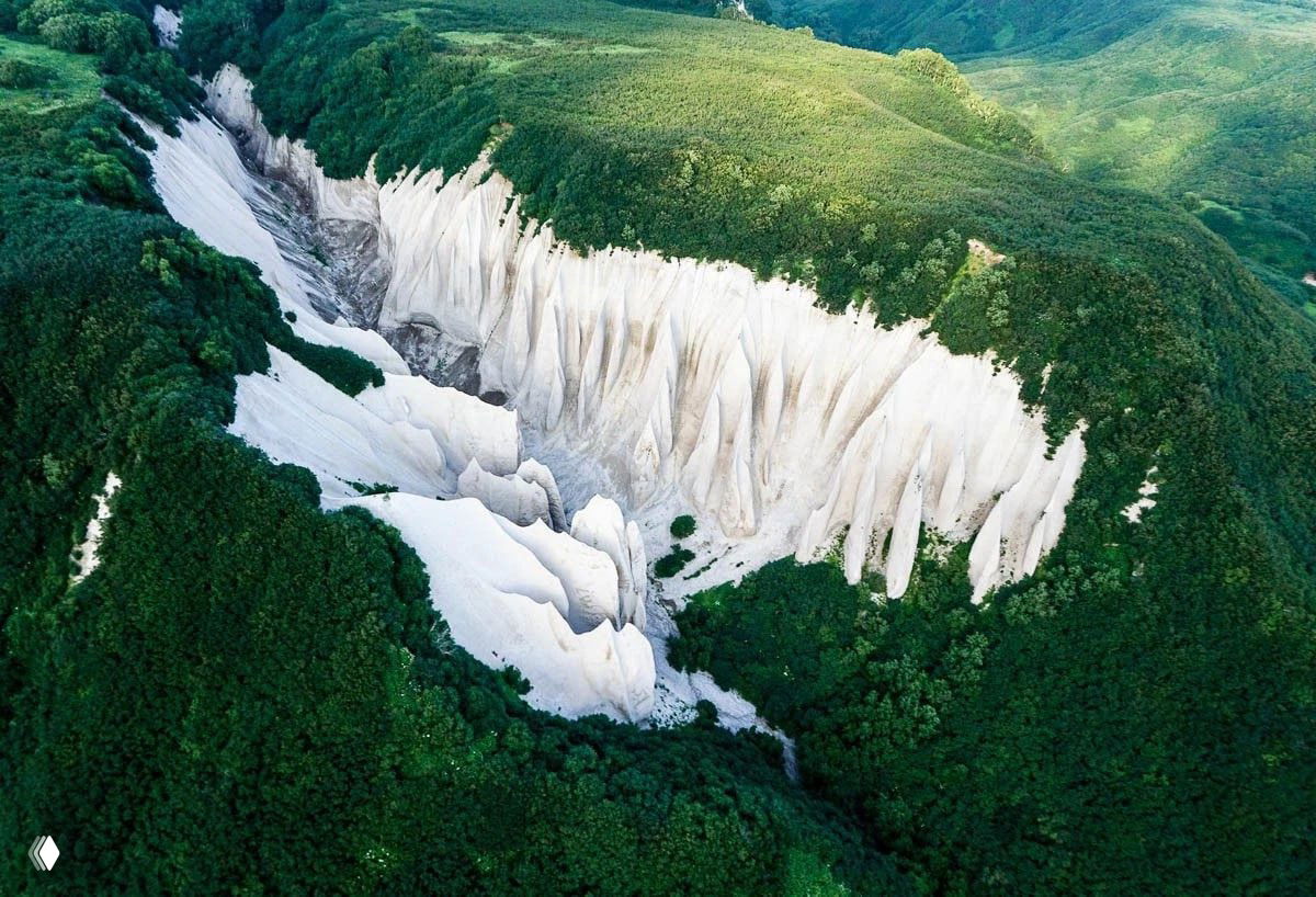 Аэровид сверху на белые пемзовые образования Кутхиных Бат среди зелёных холмов: с высоты хорошо видно масштаб и характерные формы.