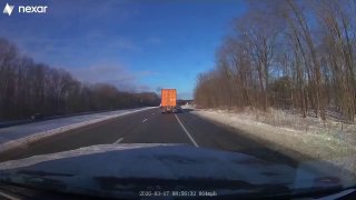 Кадр с автомобильного регистратора: зимняя двухполосная трасса в Огайо, впереди едет грузовик, по обочинам сухие деревья и чистое голубое небо.