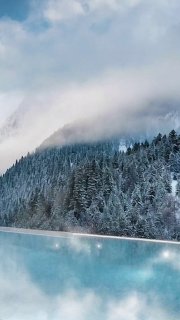 Панорамный кадр: открытый тёплый бассейн с бирюзовой водой на фоне заснеженных гор и хвойного леса в Красной Поляне.