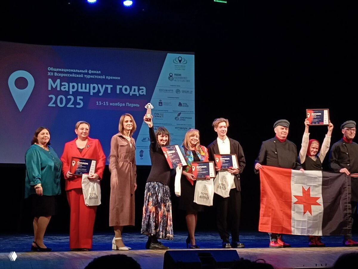 Награждение на сцене всероссийской премии «Маршрут года 2025»: группа людей с дипломами и кубками на фоне фирменного баннера фестиваля.