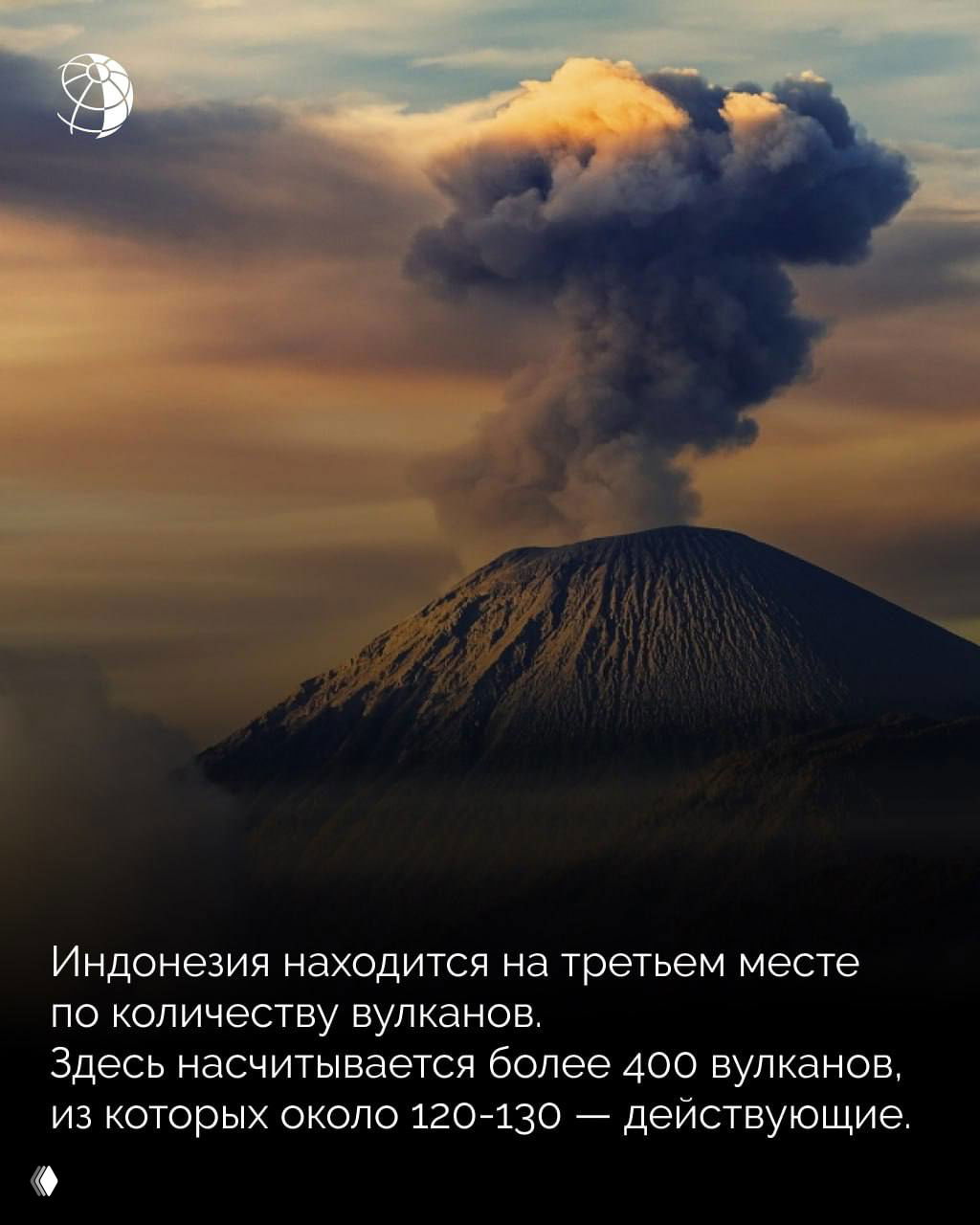 Вулкан с клубом тёмного дыма, возвышающийся над ландшафтом; изображение иллюстрирует вулканическую активность, характерную для Индонезии.