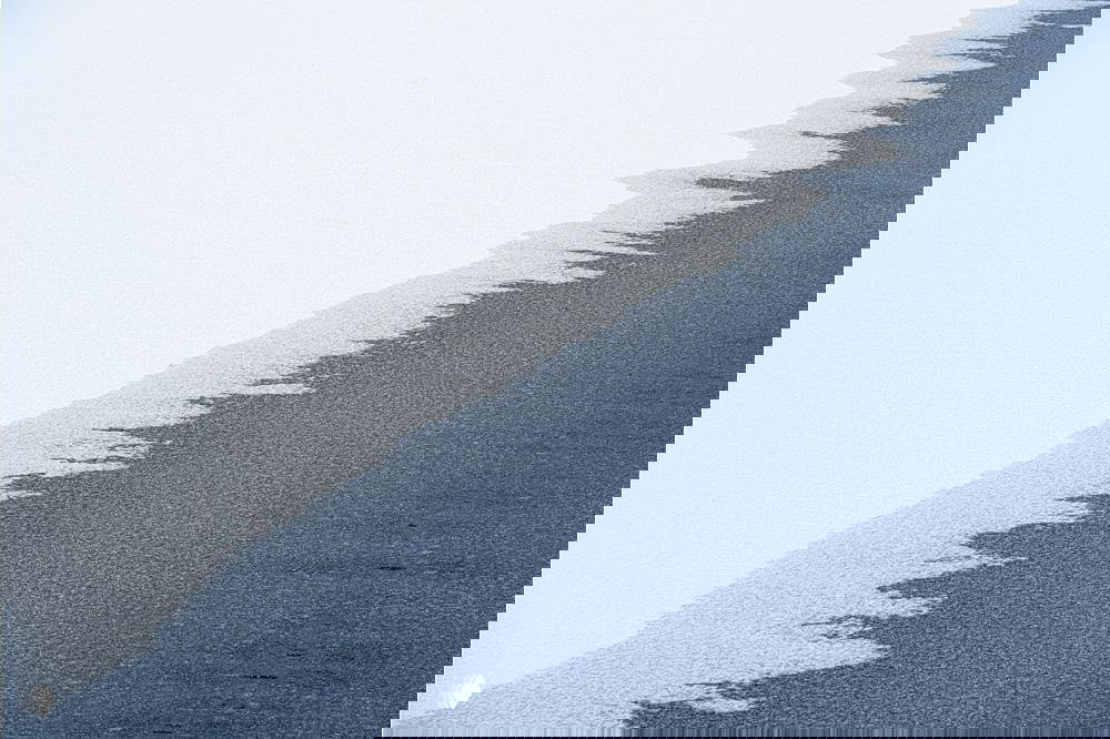 Минималистичный пейзаж: контрастный край льда и тёмной воды, акцент на текстуре и графике границы между белой и синей плоскостями