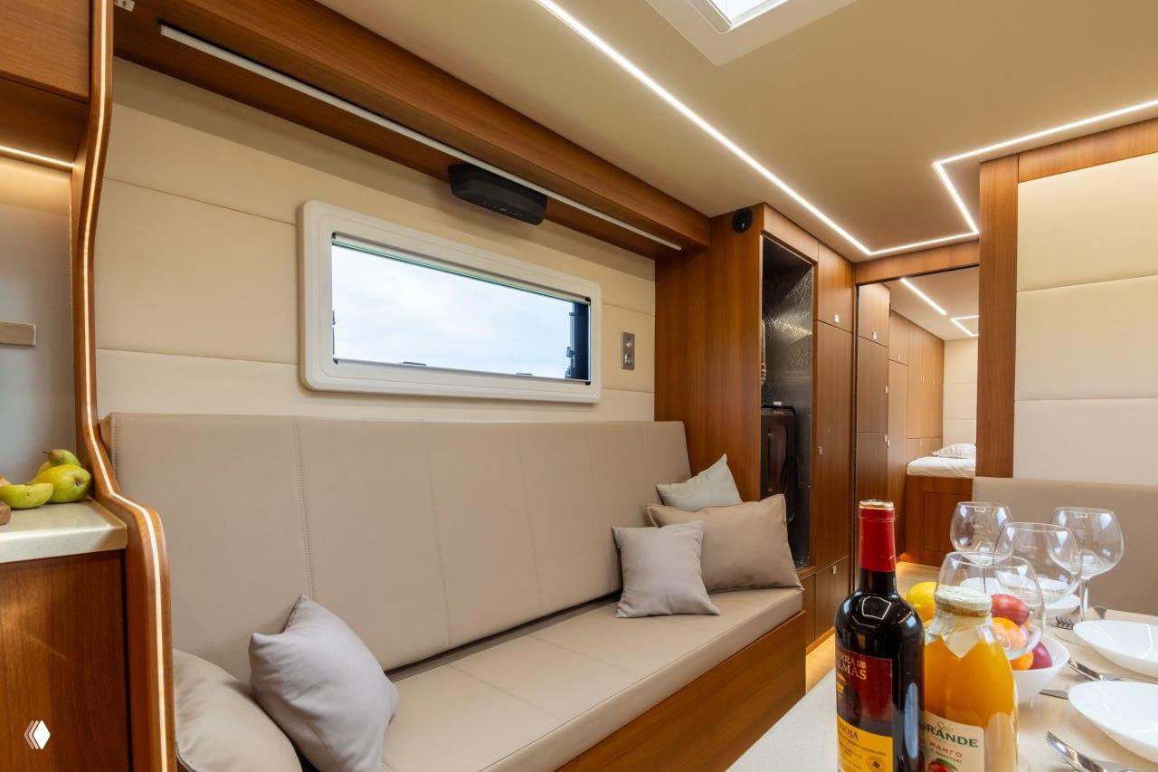 Вид на салон автодома с диваном и сервированным столом, на переднем плане бутылки и бокалы — интерьер, ориентированный на комфорт и удобство путешествий.