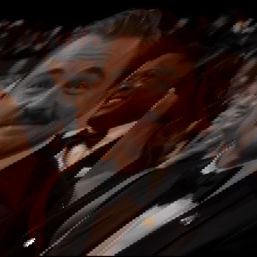 Крупный план мужчины в смокинге в зале церемонии, он улыбается в сторону сцены: кадр из зала награждения «Оскар»-2026.