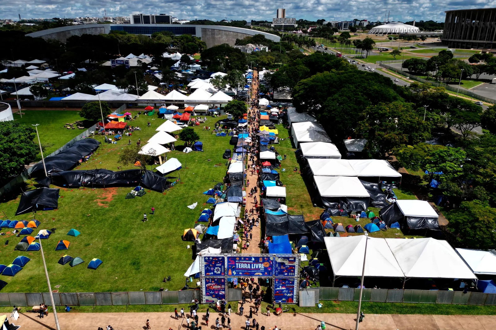 Аэрофотоснимок лагеря протестующих с рядами палаток и шатров на открытой площадке рядом с административными зданиями, вид сверху.