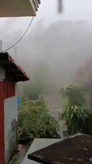 Улица населённого пункта на Филиппинах в условиях шторма: плотный дождь и сильный ветер создают низкую видимость и движение осадков по улице.