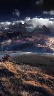 Патагонский пейзаж: горные вершины, низкие облака и ветренная травянистая равнина — иллюстрация холодного засушливого климата.