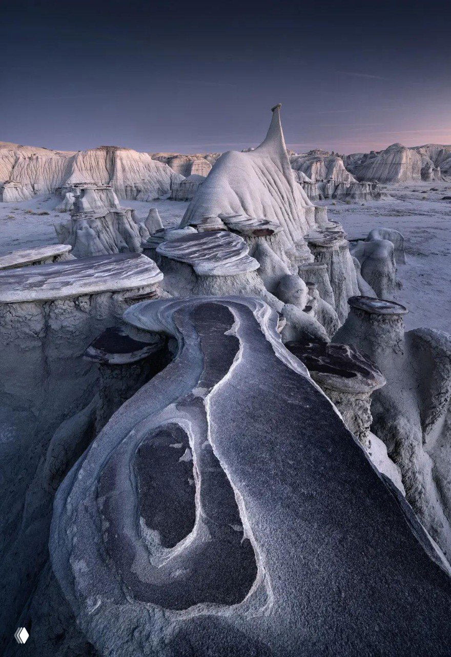 Выветренные столообразные образования и причудливые скальные платформы в монохромной гамме; текстурный ландшафт с сильным художественным эффектом.