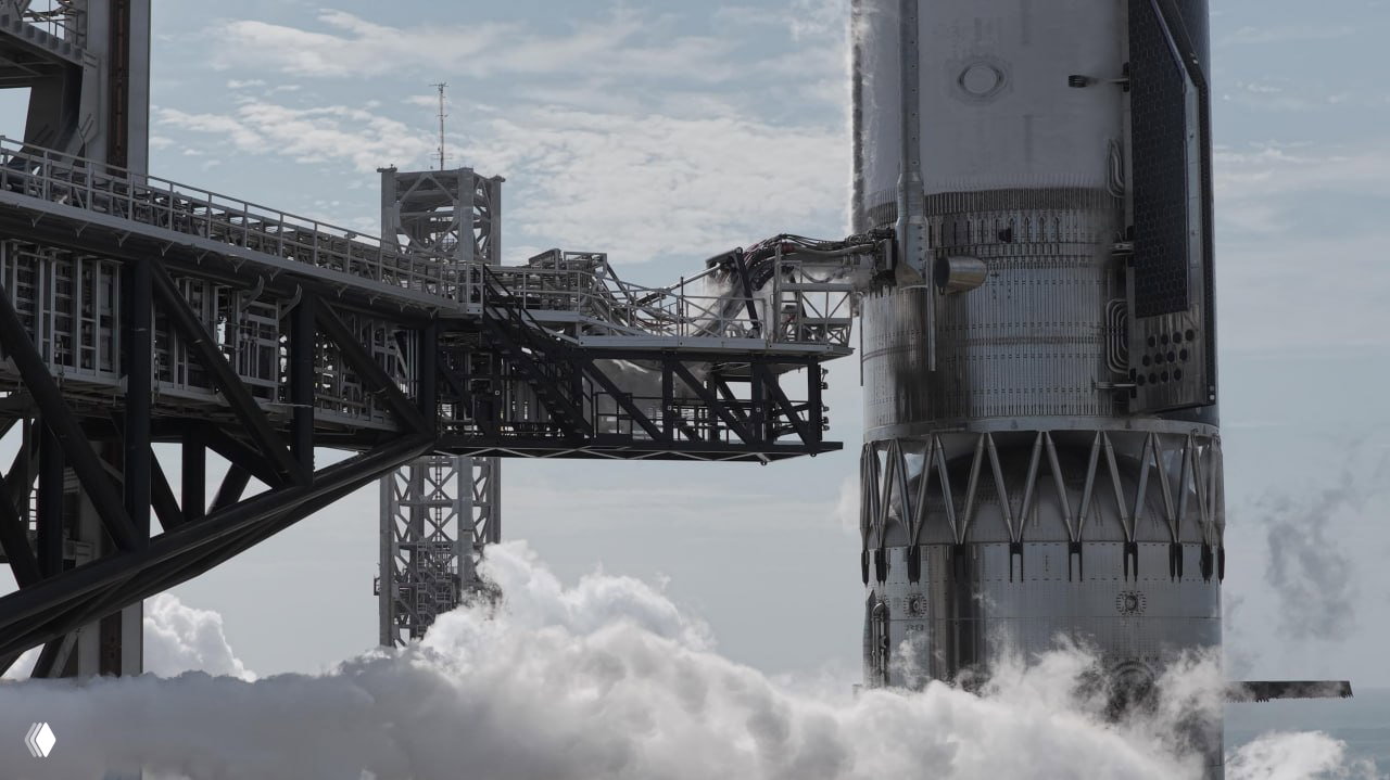 Крупный план нижней части Starship и пусковой инфраструктуры: видны опорные конструкции, элементы крепления и пар от подготовки к пуску.