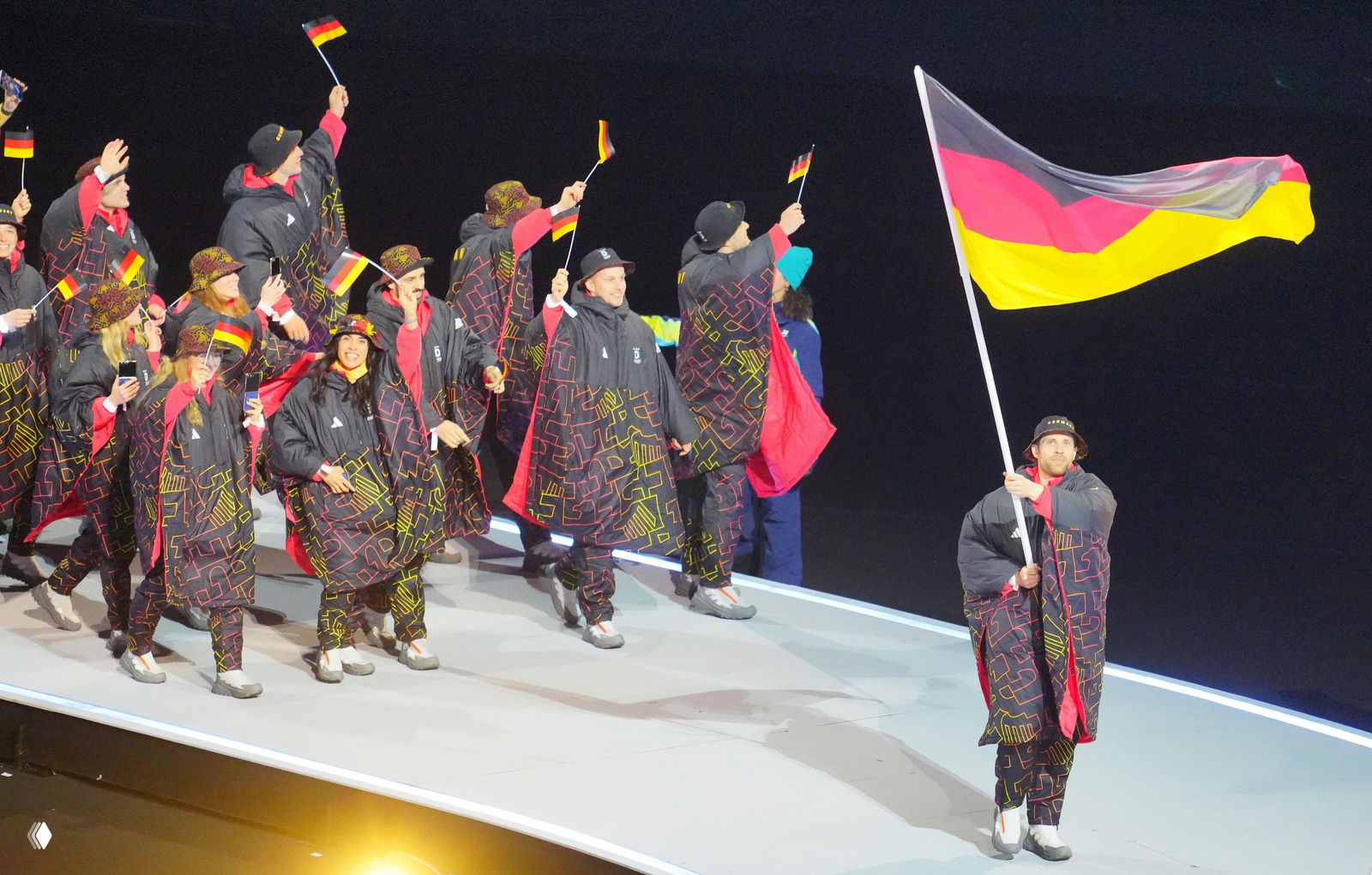 Парад команд: спортсмены Финляндии идут по дорожке с большими бело‑синими знаменами и флагами, кадр во время церемонии открытия Олимпиады.