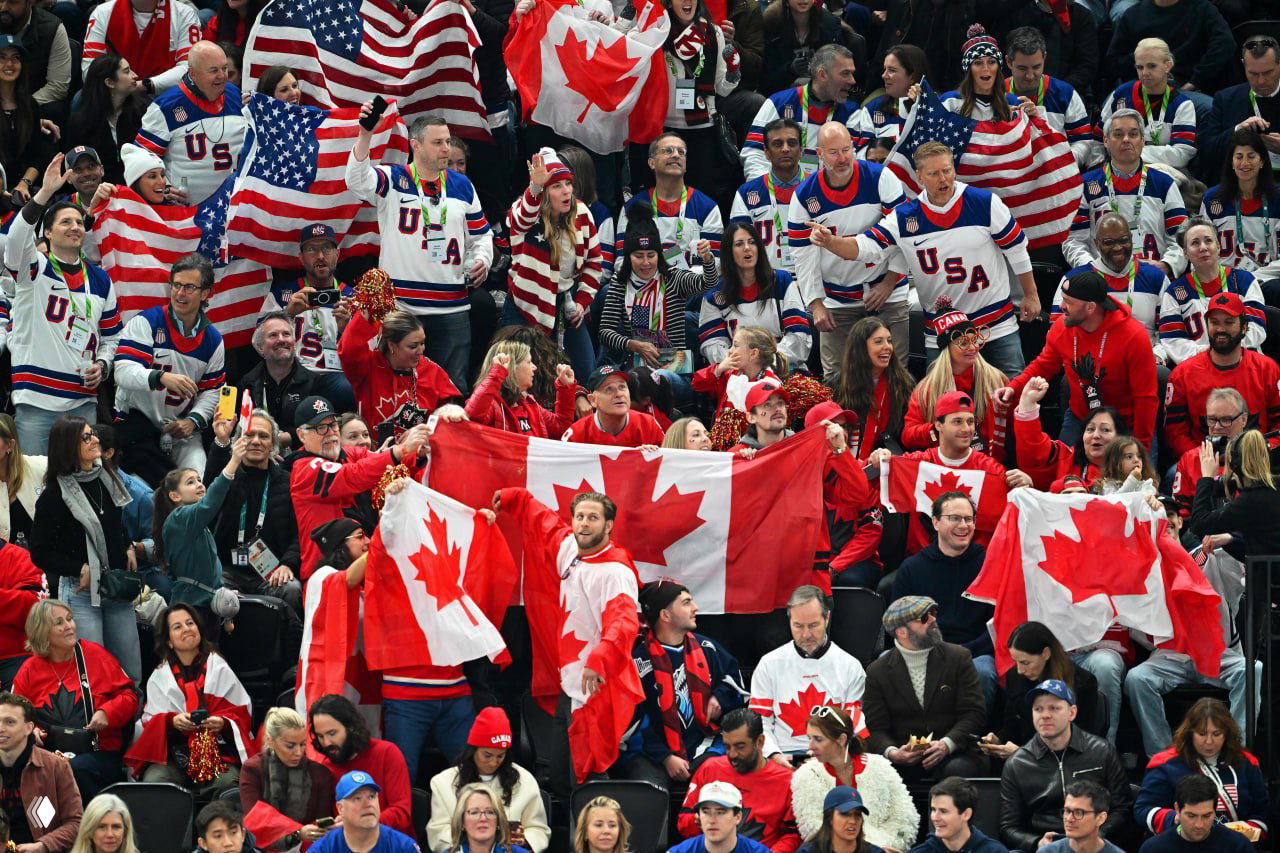 Зрители на трибунах в красной форме и с канадскими флагами болеют за сборную Канады во время финального матча по хоккею на зимних Олимпийских играх 2026 года.