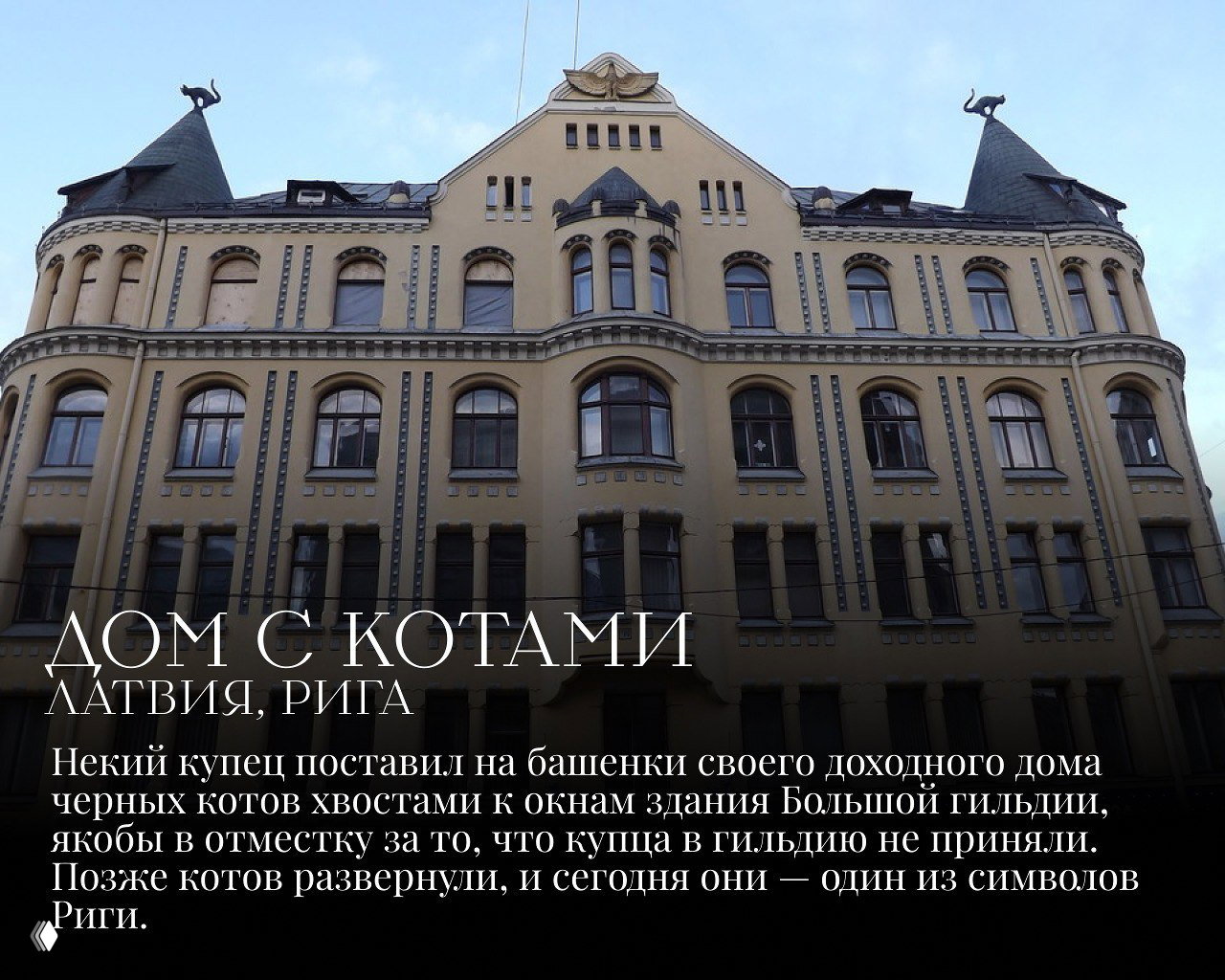Фасад рижского доходного дома с фигурками черных котов на башенках, вид архитектуры дома «с котами» на фоне неба и окон рядом расположенных зданий.