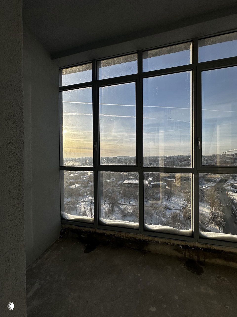 Большие оконные проёмы с видом на зимний городской ландшафт Нижнего Новгорода, снежные отложения у основания окон и просматриваемые улицы.