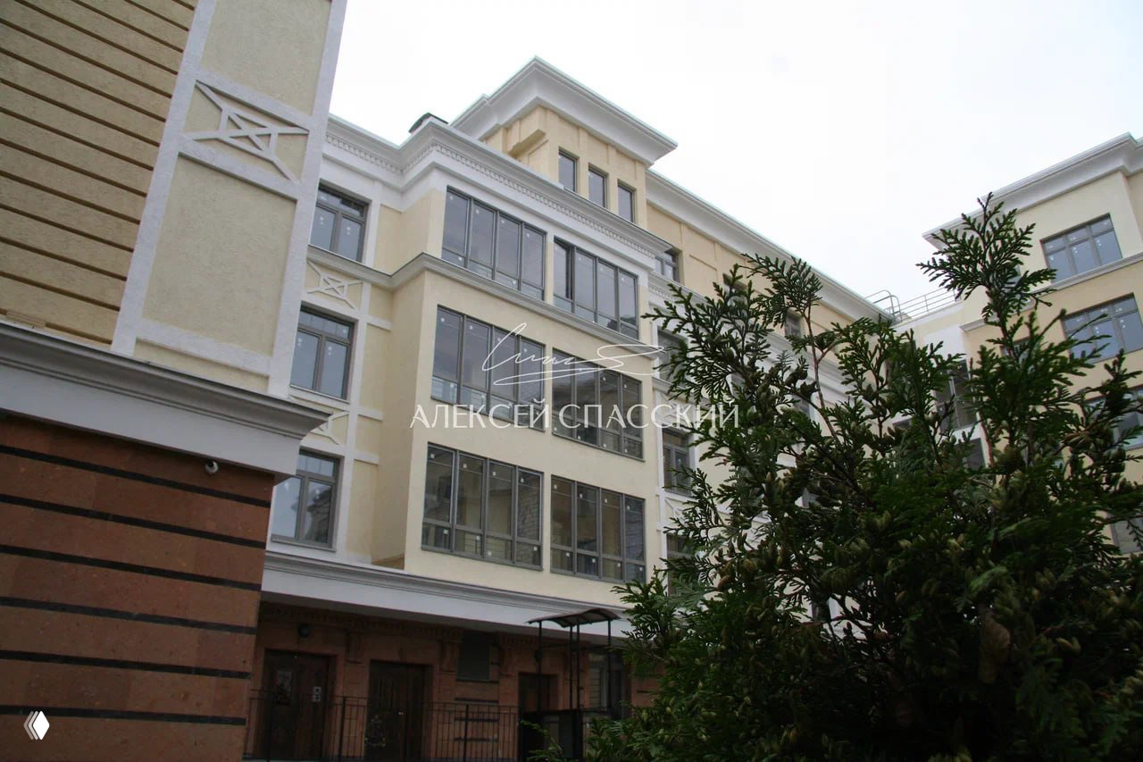 Фасадные детали и входная группа дома: светлая отделка, каменные элементы основания и стилизованные дверные проёмы у парадного входа.