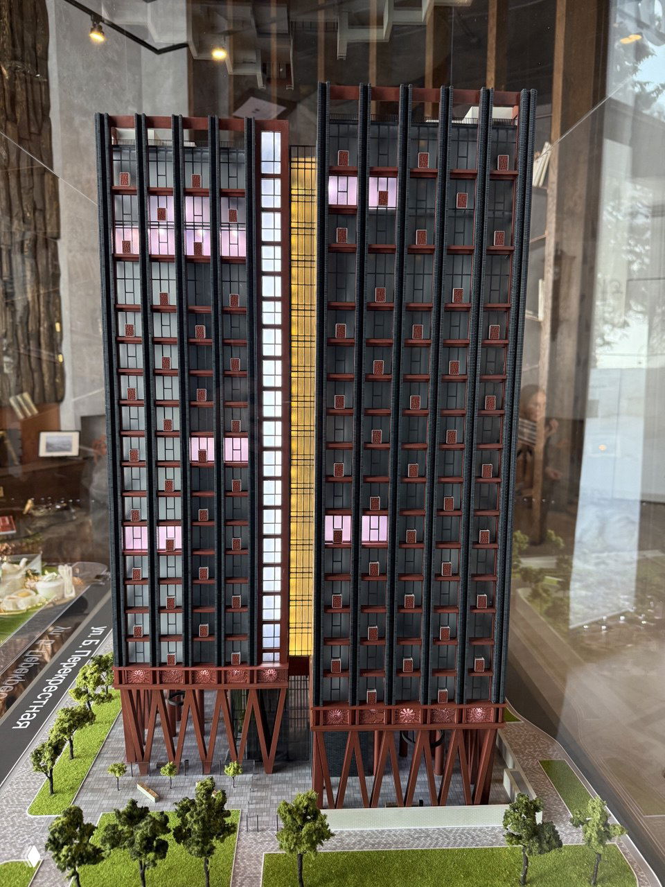 Фасад архитектурной модели Veren Place за стеклянным защитным кожухом: высотная секция, опорные колонны и планировка входной зоны видны в крупном плане.