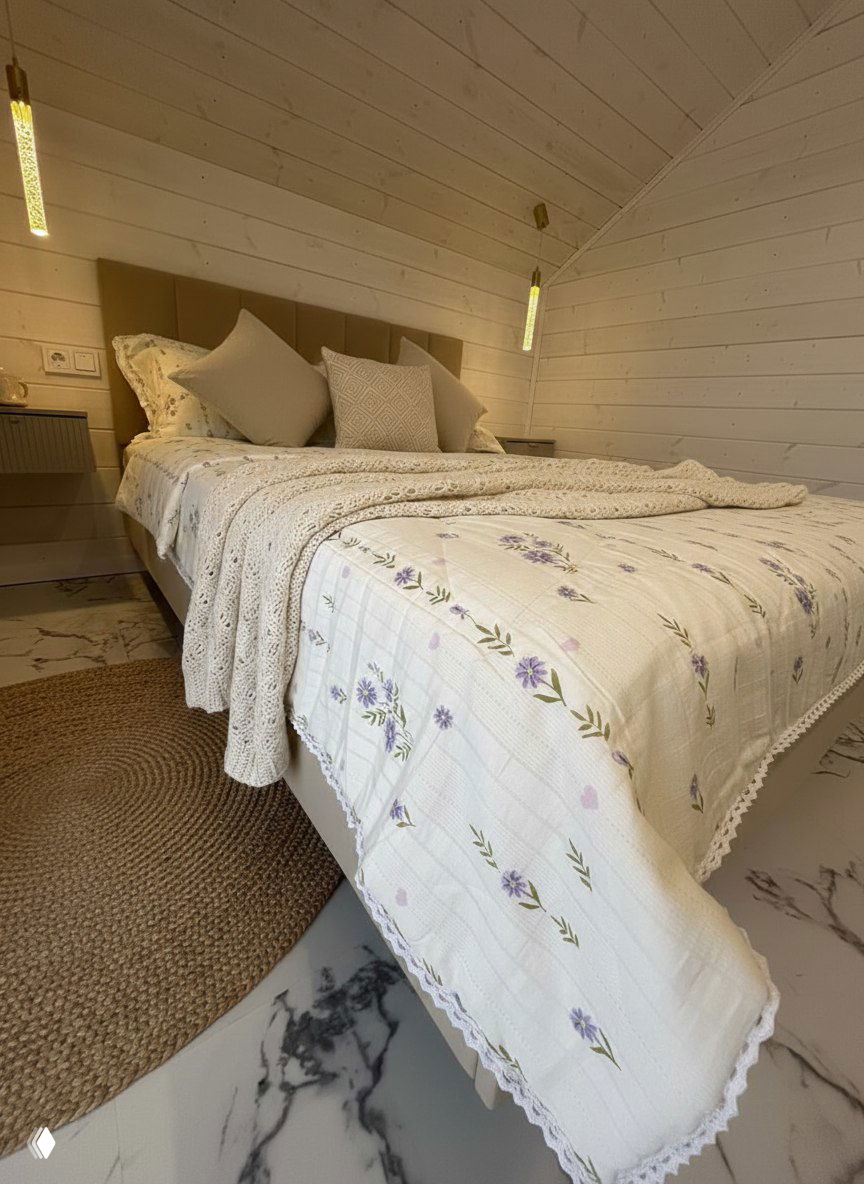 Светлое покрывало с лавандовым цветочным принтом и вязаный плед на кровати в светлой комнате — вариант текстиля от Регины.