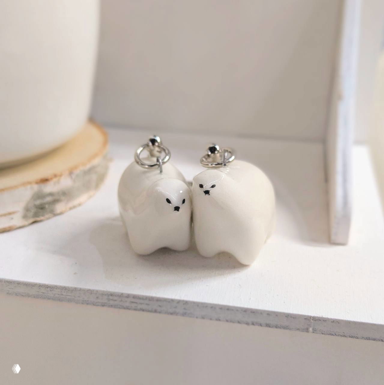 Крупный план миниатюрных белых керамических фигурок-брелоков, пара аккуратных форм на белой полке в минималистичной витрине.