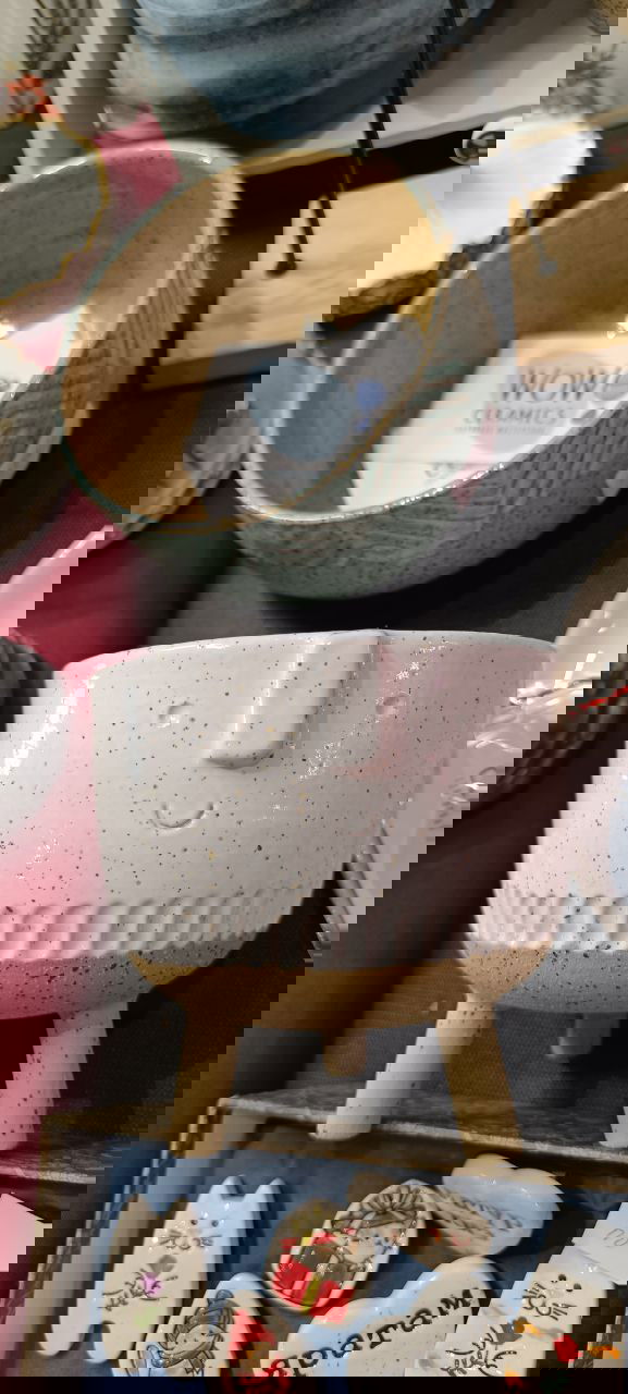 Керамические кашпо с принтами и росписями на деревянной полке; видны декоративные ножки, стёганые поверхности и ценники на некоторых изделиях на маркете.