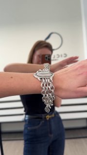Запястье в зеркале с длинным многослойным браслетом Ciclon — демонстрация веса и посадки украшения на руке покупательницы.