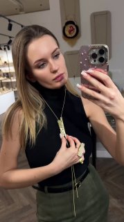 Портретная фотография модели у зеркала в бутике Rosone с длинным кулоном KALLIOPE на шее и серьгами, демонстрация образа.