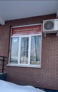 Фасад с оформленным окном школы английского: окно на плёнке и наружный блок кондиционера — пример сотрудничества.