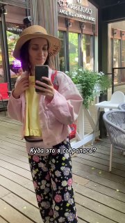 Селфи автора в шляпе и розовой куртке на летней уютной веранде кафе в Аптекарском: столики, растения и отражение витрины.