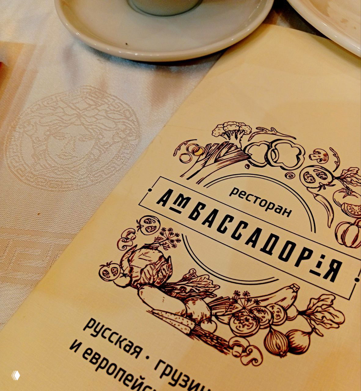 Близиный план меню ресторана «Амбассадория» на столе с чашкой — место приёма гостей и обсуждений после встречи литераторов.