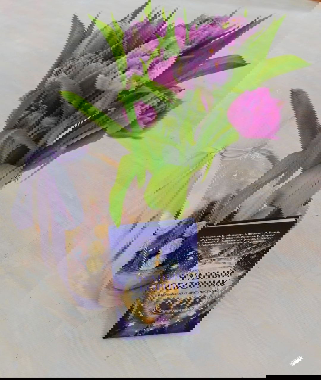 Букет сиреневых тюльпанов рядом с экземпляром книги «Чудный сборник» на столе — фотография со стола презентации, атмосферный реквизит и подарок.