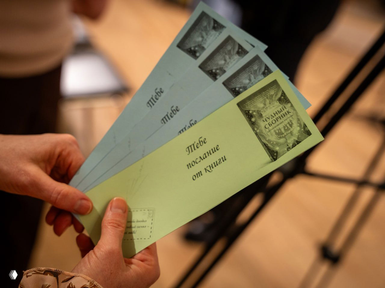 Руки держат несколько закладок с надписью «Тебе послание от книги» — элемент мероприятия и небольшое участие гостей во время презентации.