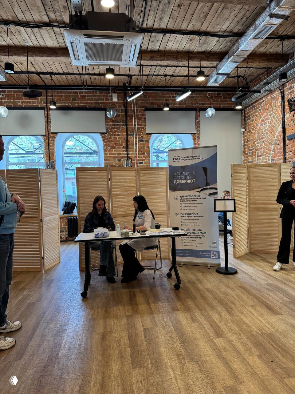 Общий вид зоны клиники на форуме: стол приёма, ролл-ап с информацией и перегородки в пространстве креативного кластера Домна.